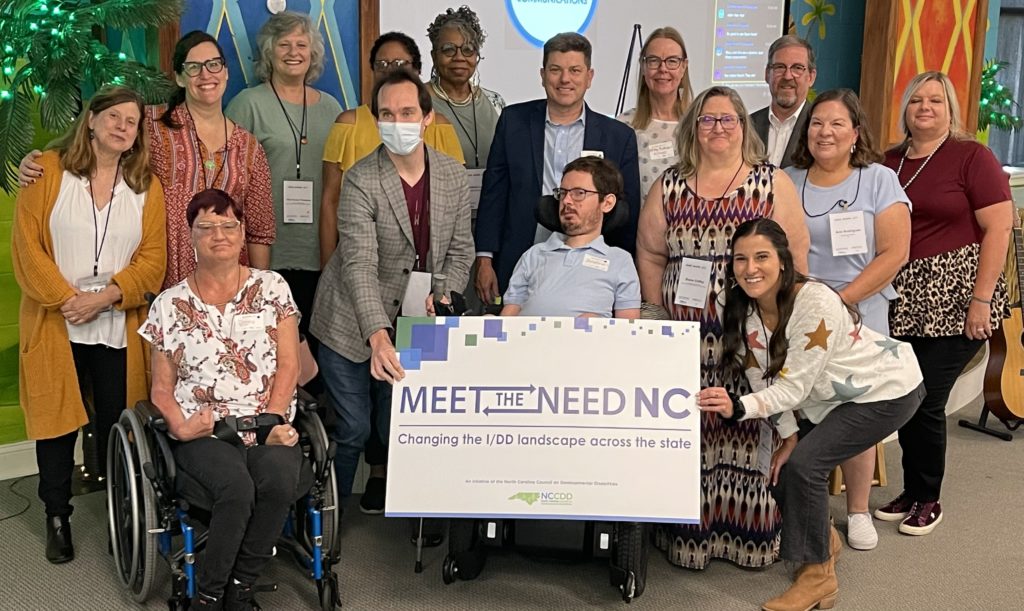 Group of people around a sign that reads Meet the Need NC